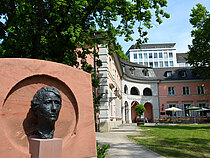Das Denkmal von Louise Dumont mit den historischen Hofgartenhaus im Hintergrund