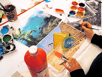 Foto mit Farben, Pinseln, Papier und malenden Kinderhänden