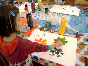 Foto mit Farben, Pinseln, Papier und malenden Kindern